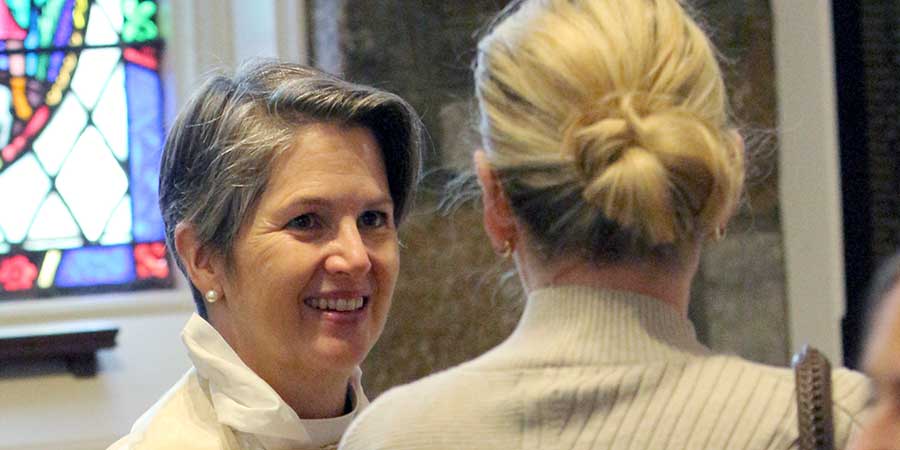 One woman episcopal priest greeting a woman with her back to the camera — Soul Sisters Event